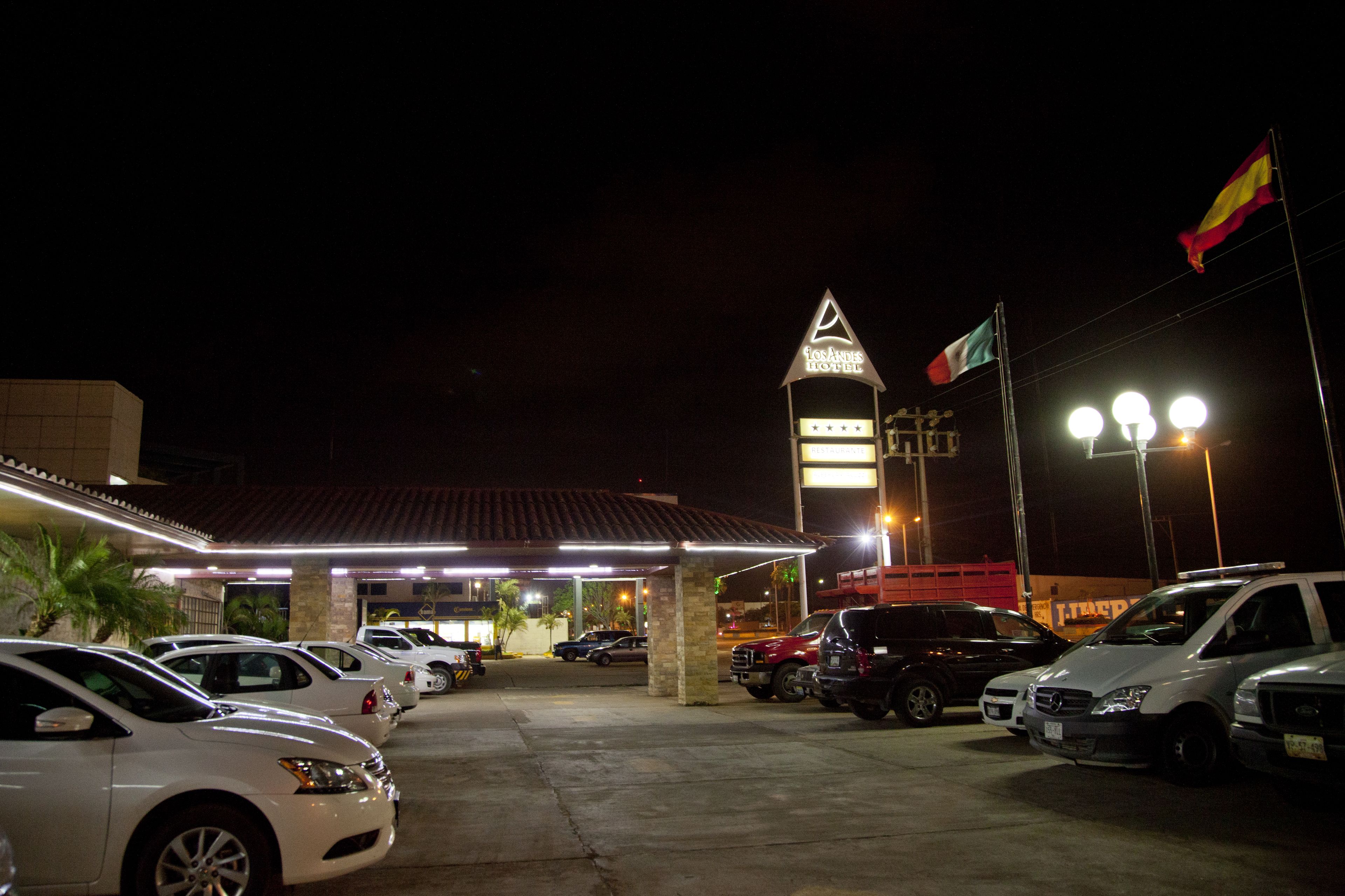 Un hotel con una torre destacada y un estacionamiento lleno de coches.