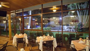 A restaurant with tables set for dining, large windows, and a view of the outdoor area. - Hotel Los Andes (Coatzacoalcos)