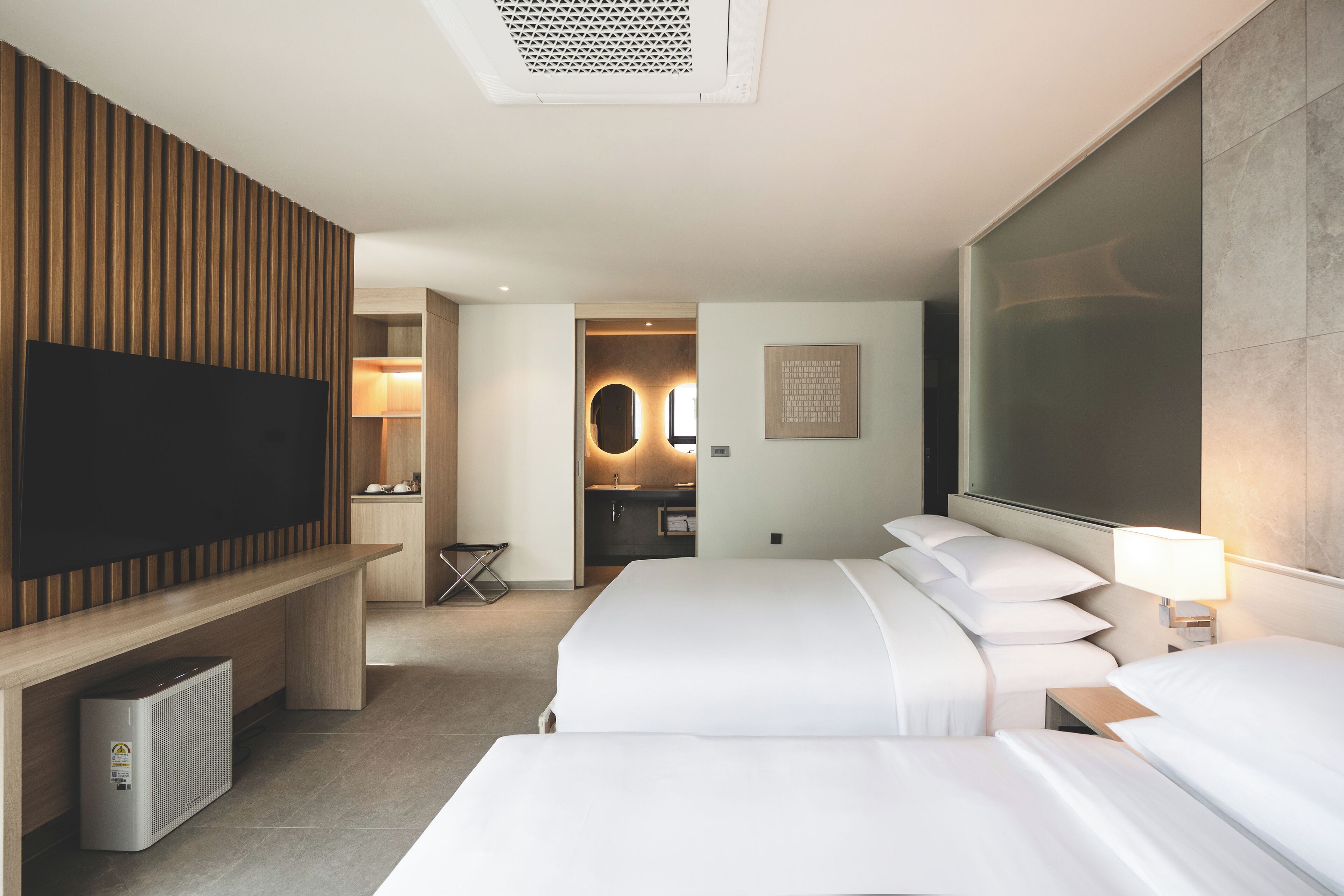 A hotel room with a large bed, a TV, a desk, and a bathroom visible through an open door.