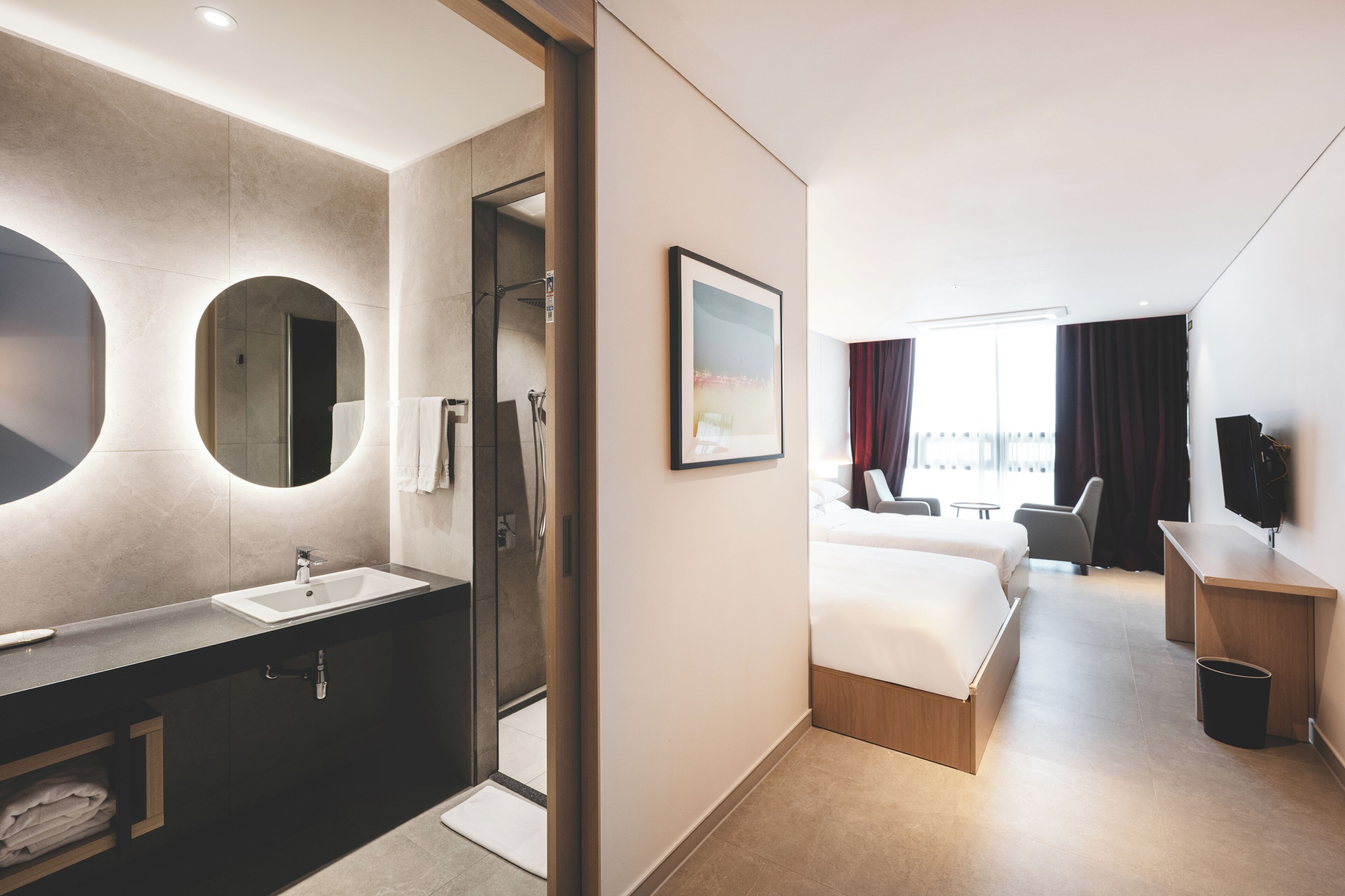 Una habitación de hotel moderna con baño, cama, escritorio y televisor.