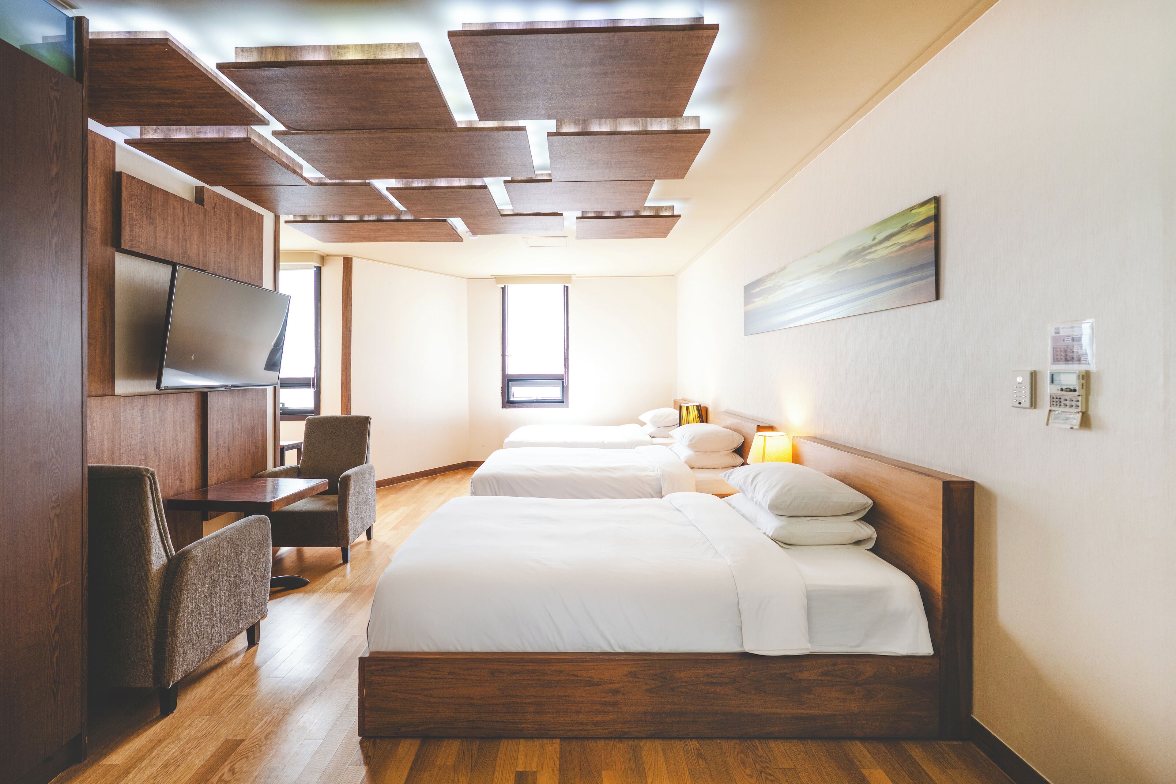 Habitación de hotel con dos camas, televisión, escritorio y ventana.