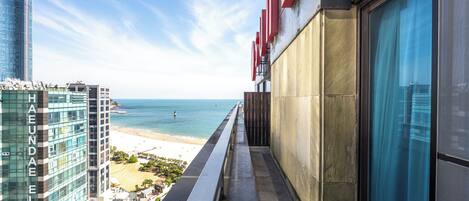 A balcony with a view of a beach and a high-rise building.