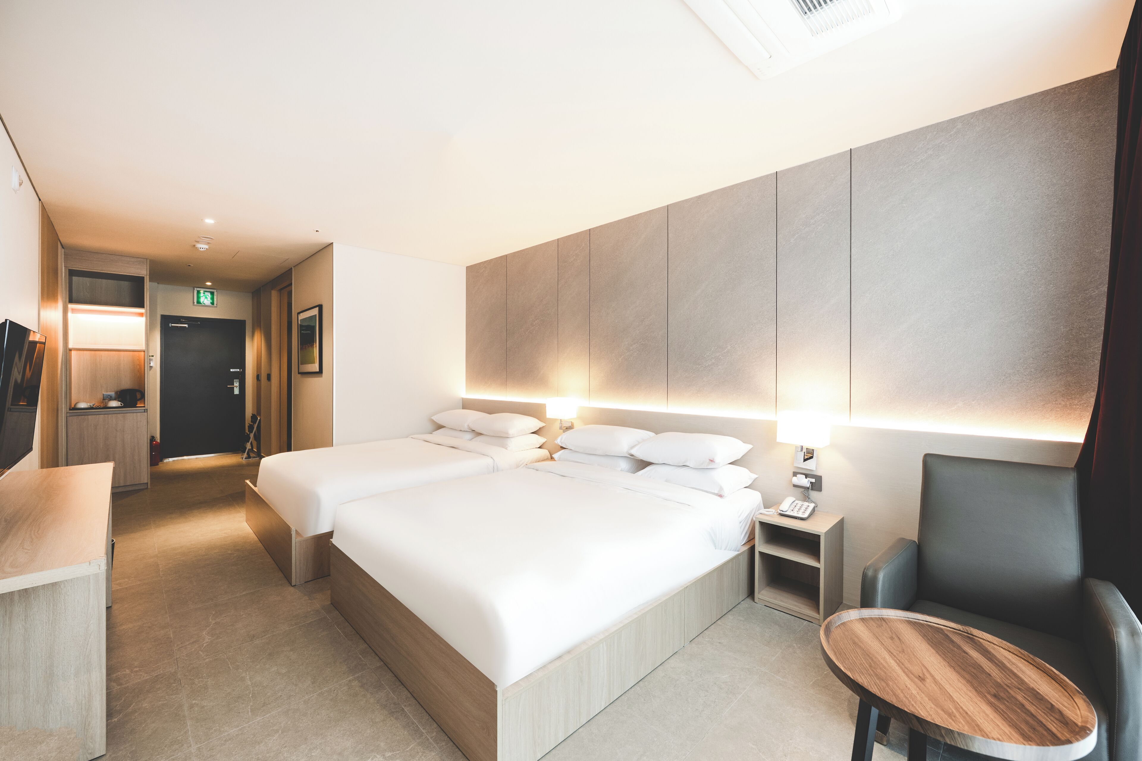 Una habitación de hotel con una cama grande, mesitas de noche, un escritorio y una silla.