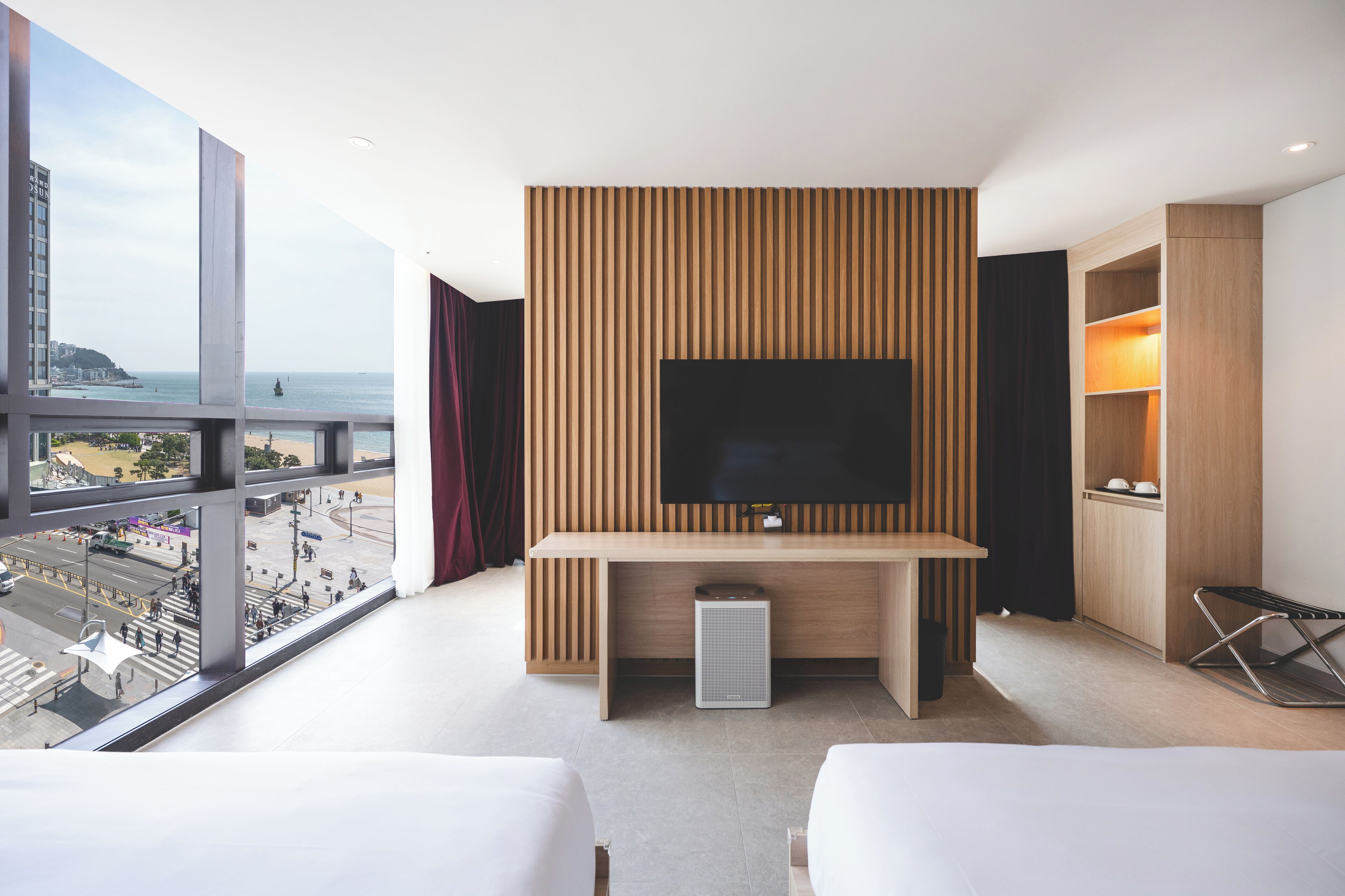 Une chambre d’hôtel dotée d’une grande télévision, d’un mur revêtu de panneaux en bois et offrant une vue sur la ville.