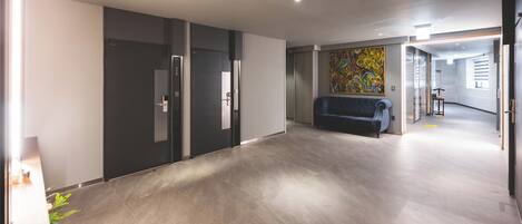 A modern hallway with a dark-colored sofa, a large abstract painting on the wall, and a door labeled '7'.