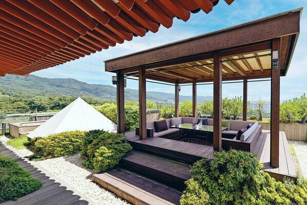 Un patio al aire libre con terraza de madera, zona de estar y vistas a las montañas.