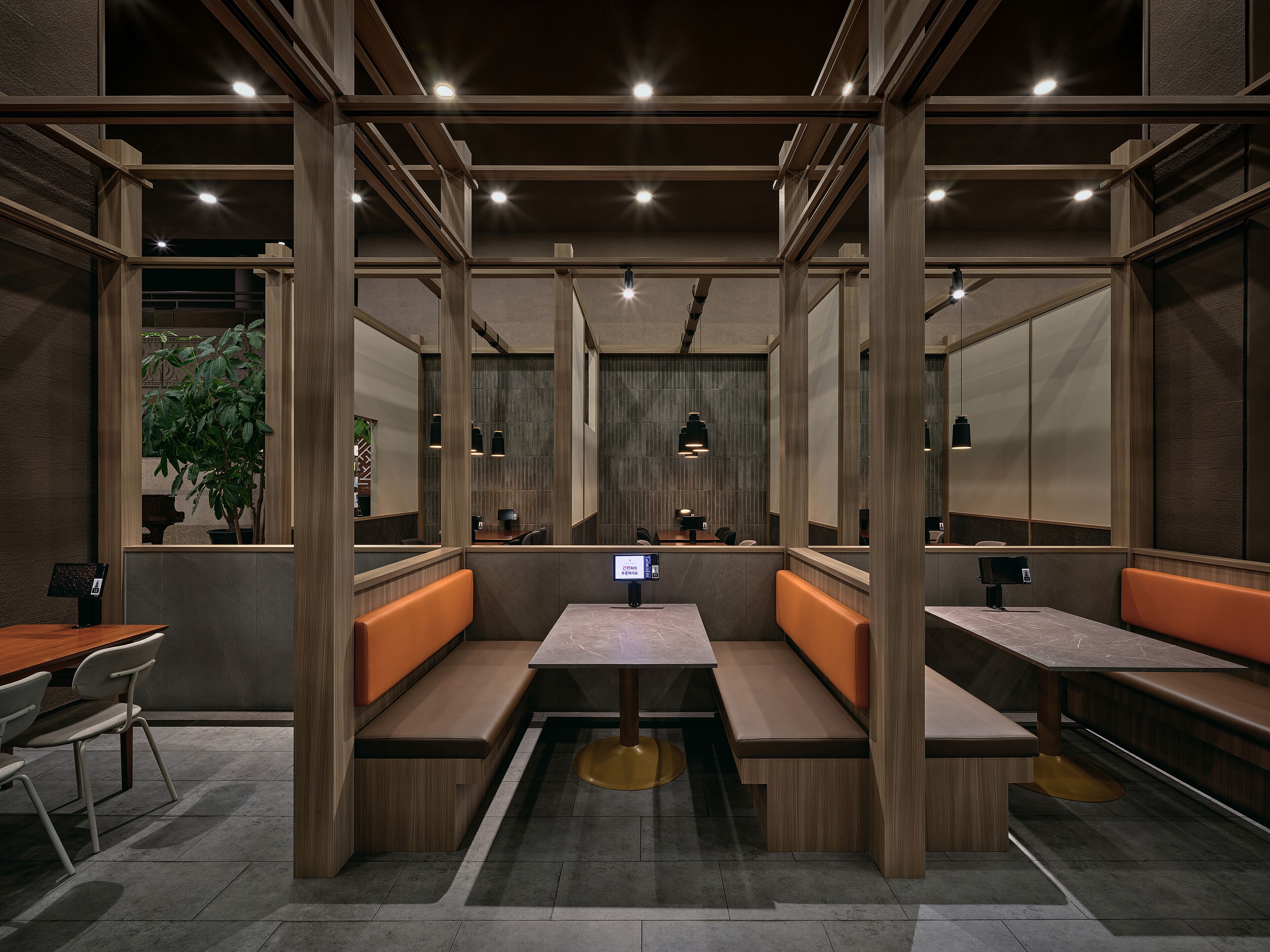 A modern restaurant with wooden booths, a central table, and pendant lighting.