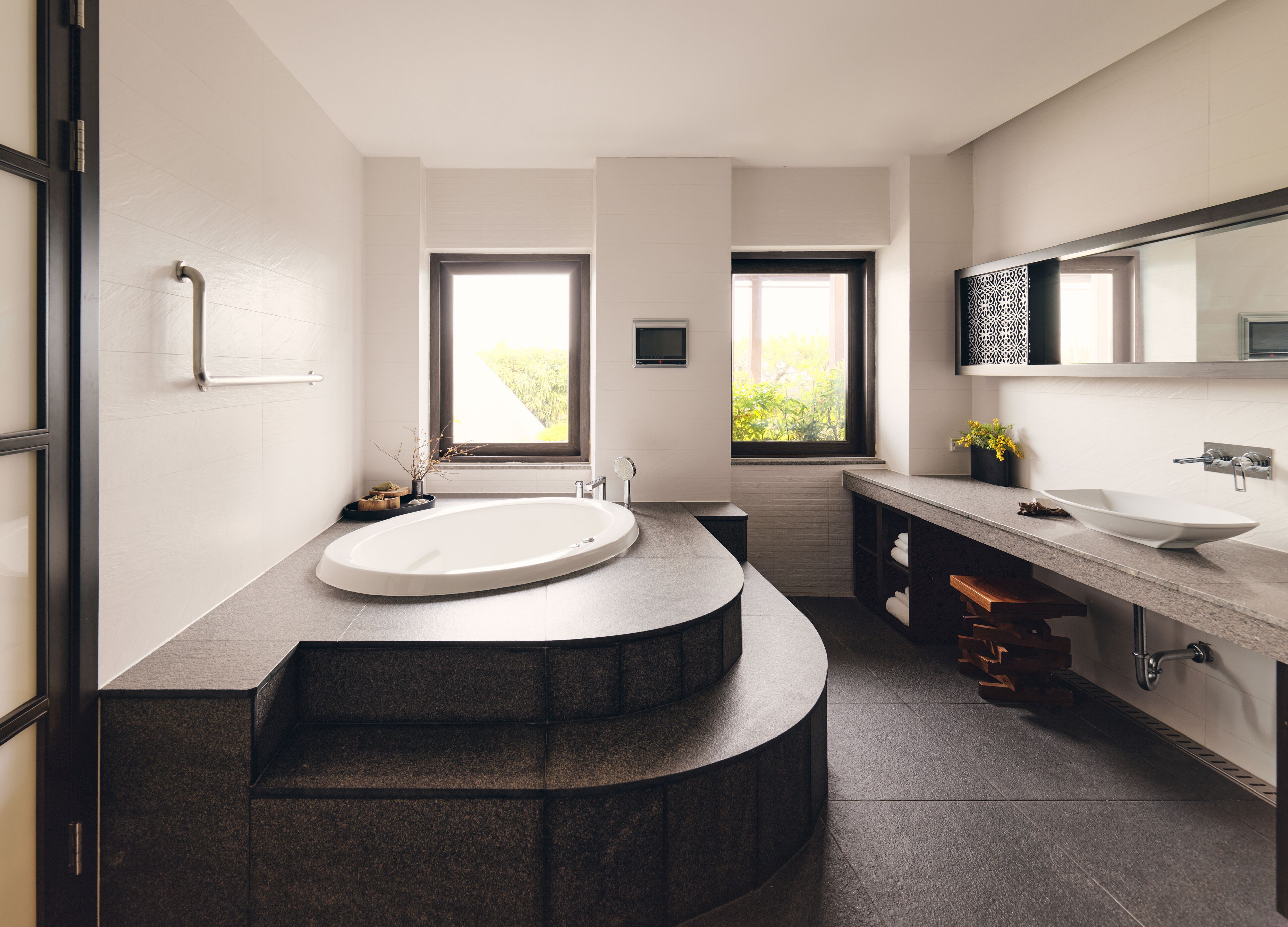 Une salle de bain moderne avec un grand lavabo ovale, un meuble-lavabo aux lignes courbes et une fenêtre laissant entrer la lumière naturelle.