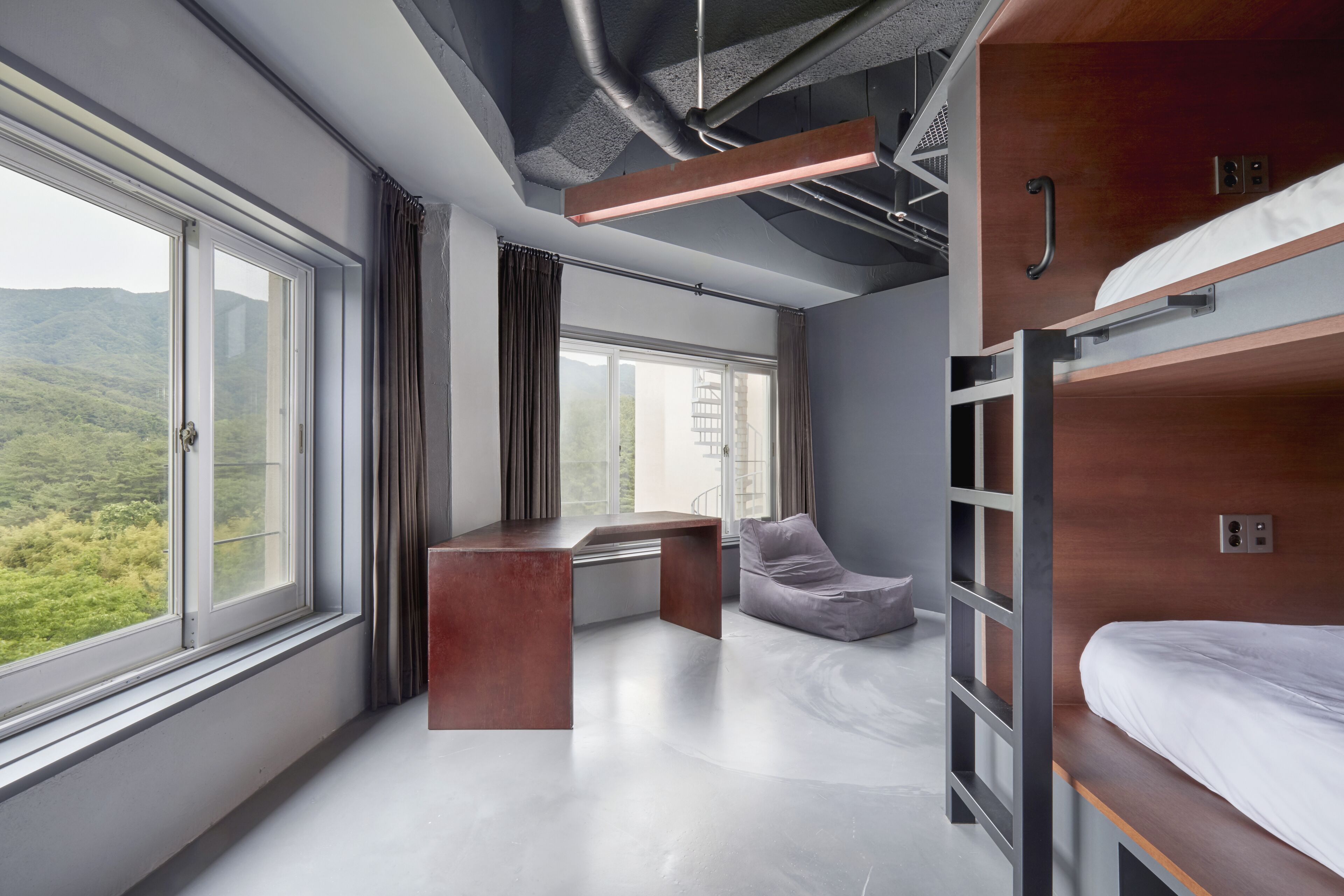 Ein modernes Zimmer mit Etagenbetten, einem Schreibtisch und Blick auf Grünflächen.