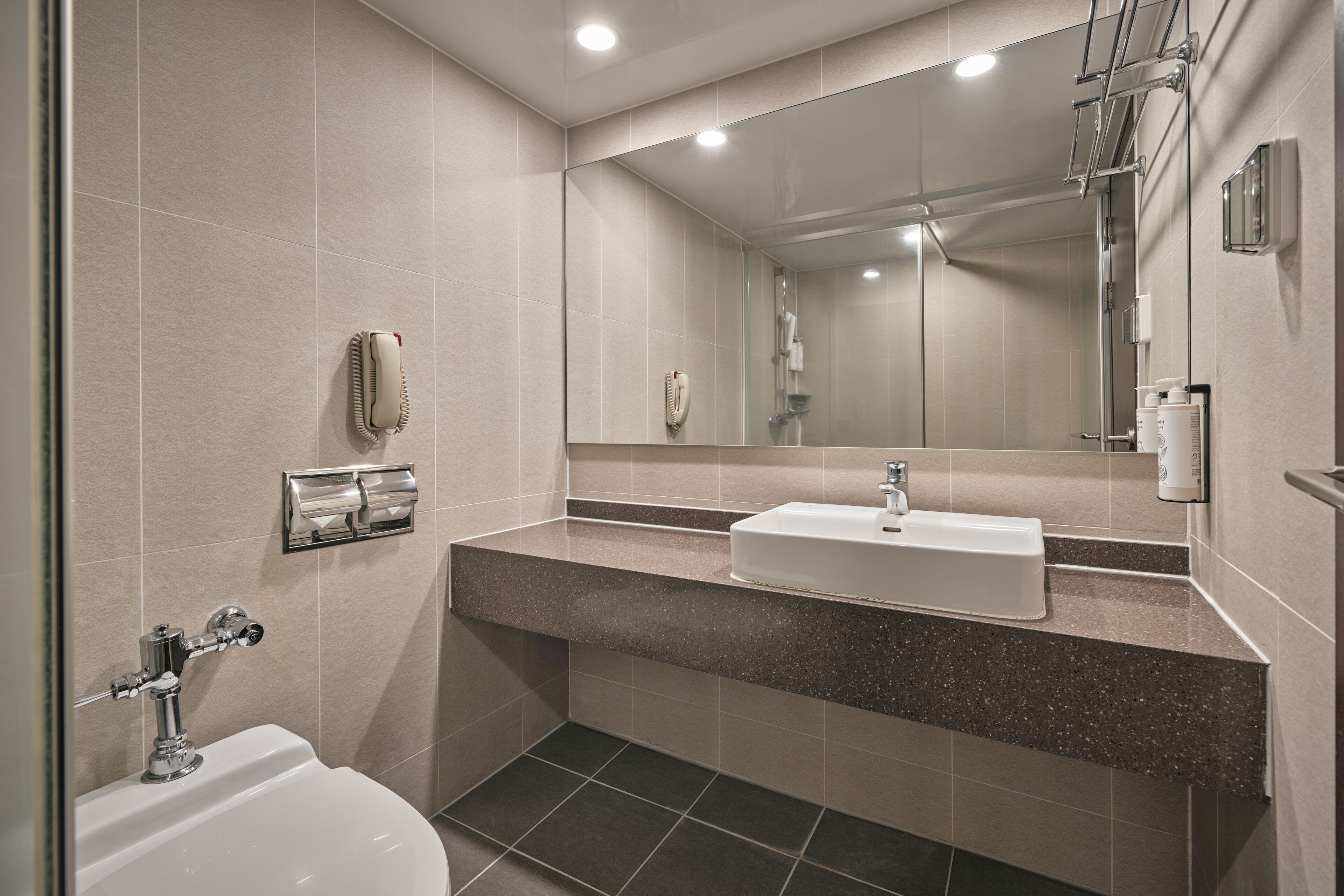 Un baño moderno con un lavamanos blanco, un espejo grande y una zona de ducha.