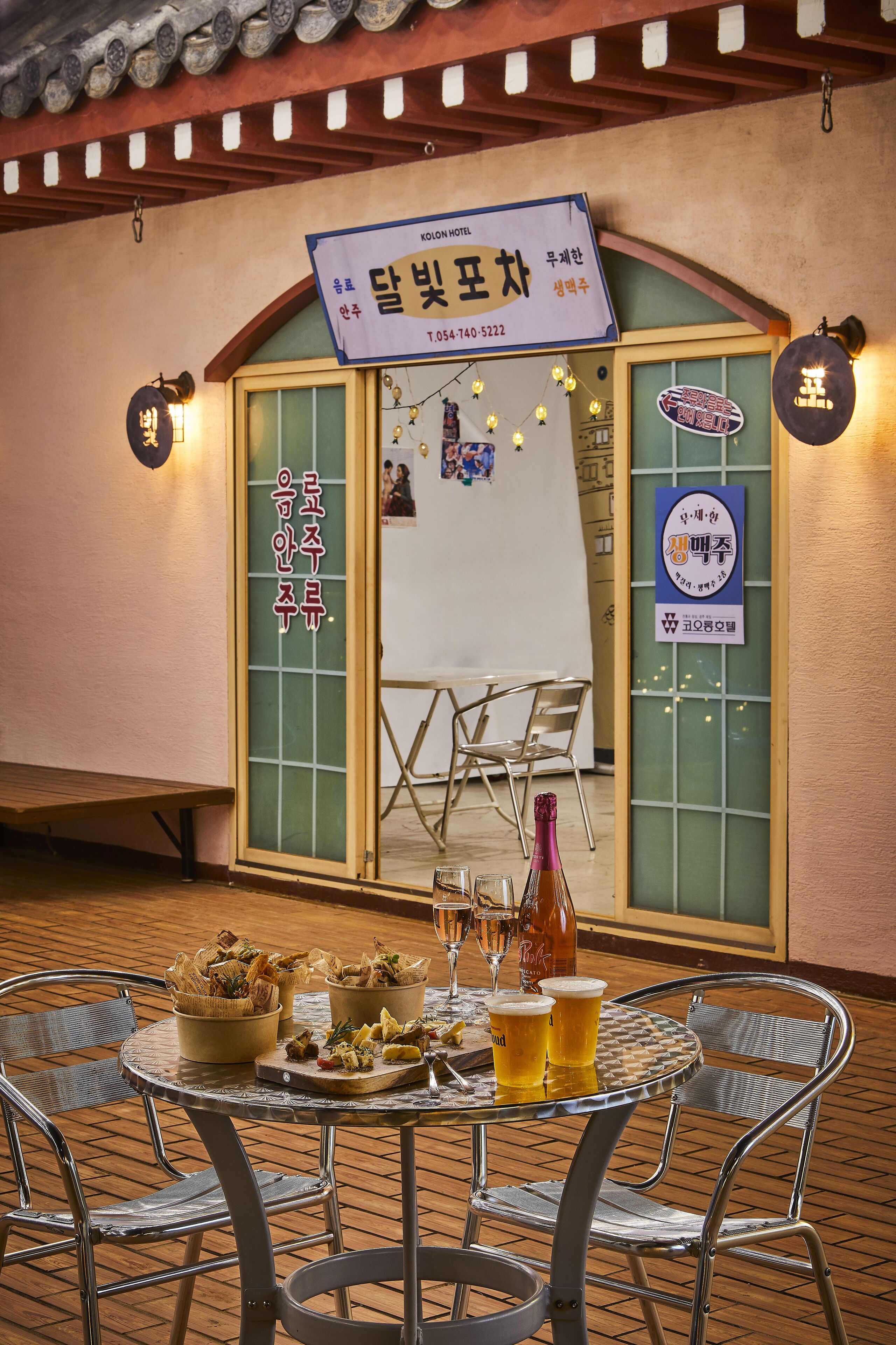 A restaurant with a traditional Korean sign, a table set with food and drinks, and a view of the interior.