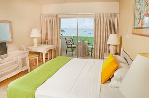 Habitación de hotel con cama, escritorio, silla, televisión y balcón con vista al mar.