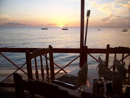 Un restaurante frente al mar, con vistas al océano y a los barcos al atardecer.