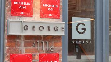 En murstensbygning med skilt for 'GEORGE' og Michelin-stjerner for 2022, 2023, 2024 og 2025.