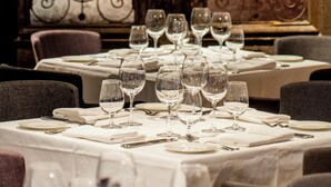 Un comedor con mesas dispuestas para una comida, con puertas de metal ornamentales al fondo.