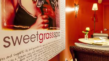 Een restaurantinterieur met een advertentie op de muur voor Sweetgrass Spa, een eettafel met stoelen en een kleine potplant.