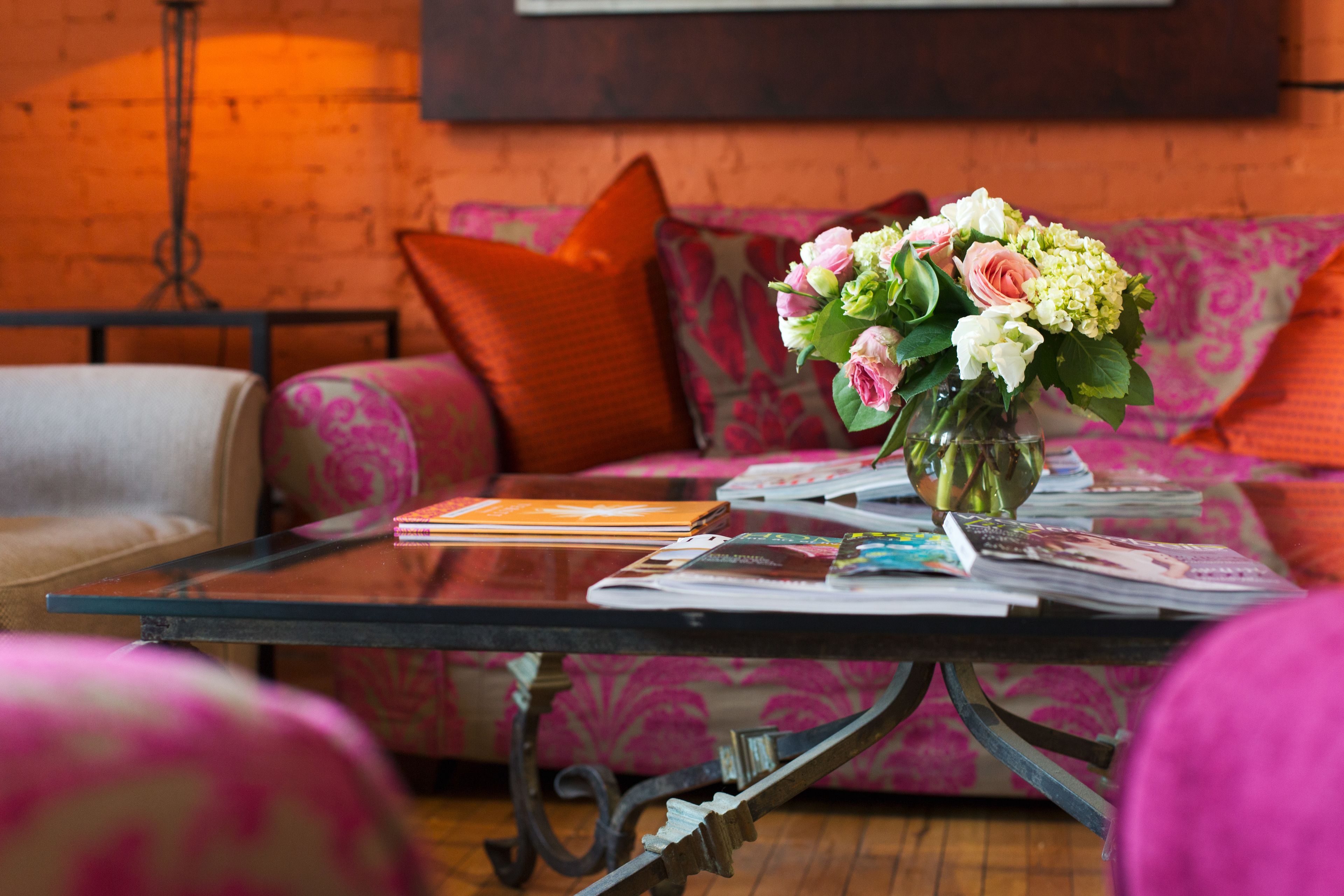 A cozy living area with a sofa, a coffee table with magazines, and a vase of flowers.