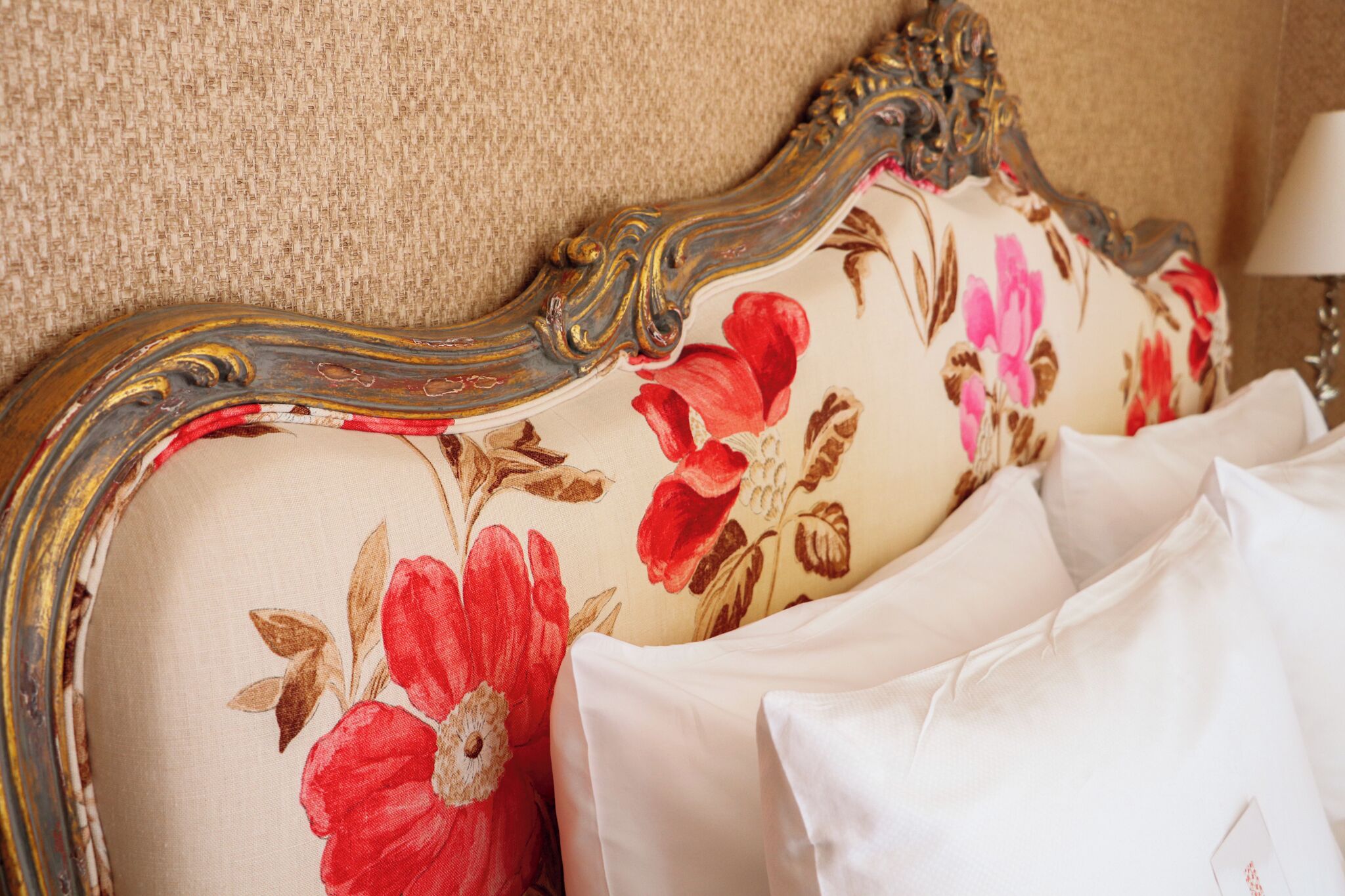 Un lit avec une tête de lit à motifs floraux et des oreillers blancs.
