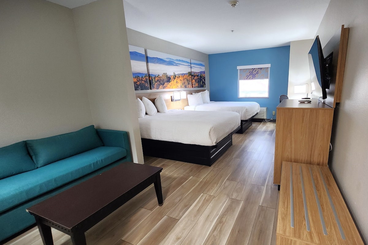 Una habitación de hotel con cama, sofá, escritorio y televisión.