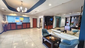 A hotel lobby with a reception desk, seating area, and a television.