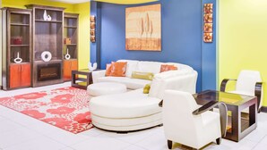 A living room with a white sofa, a glass coffee table, and a red patterned rug.