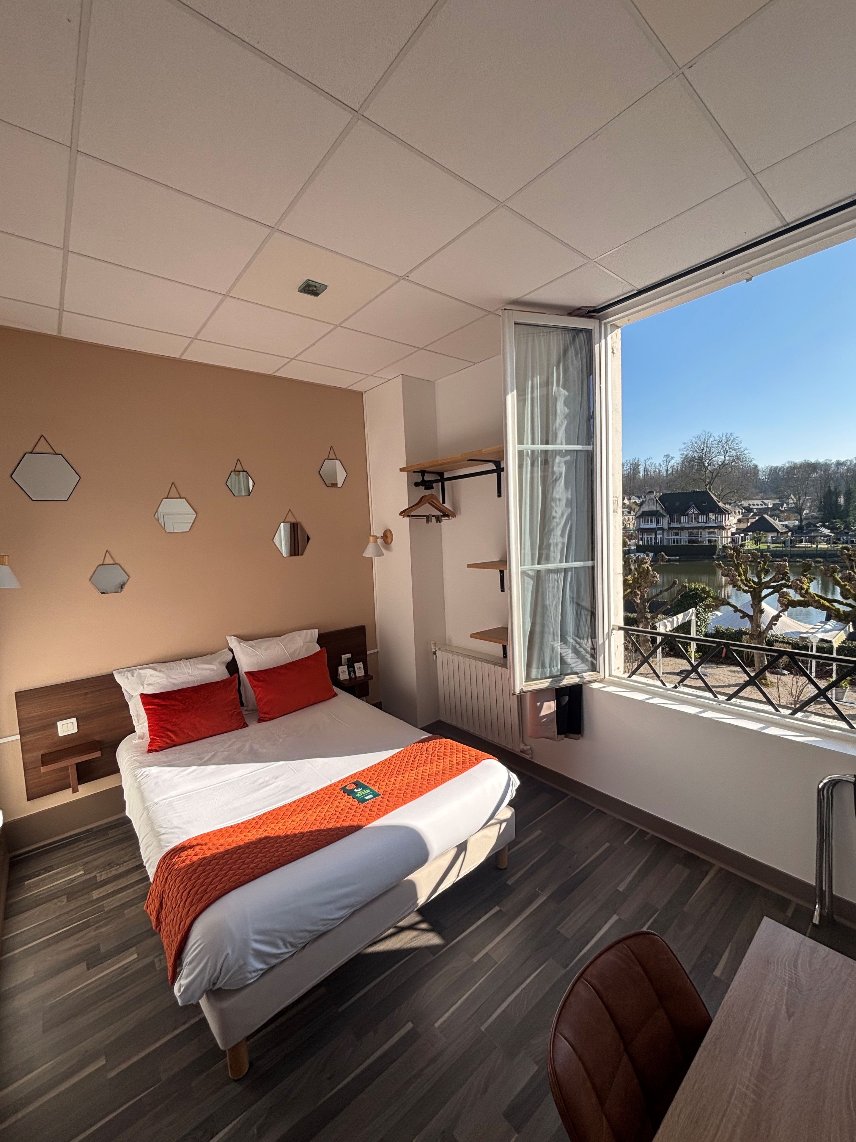 A modern hotel room with a large bed, a view of the city, and a balcony.