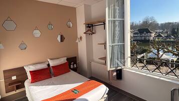 A modern hotel room with a large bed, a view of the city, and a balcony.