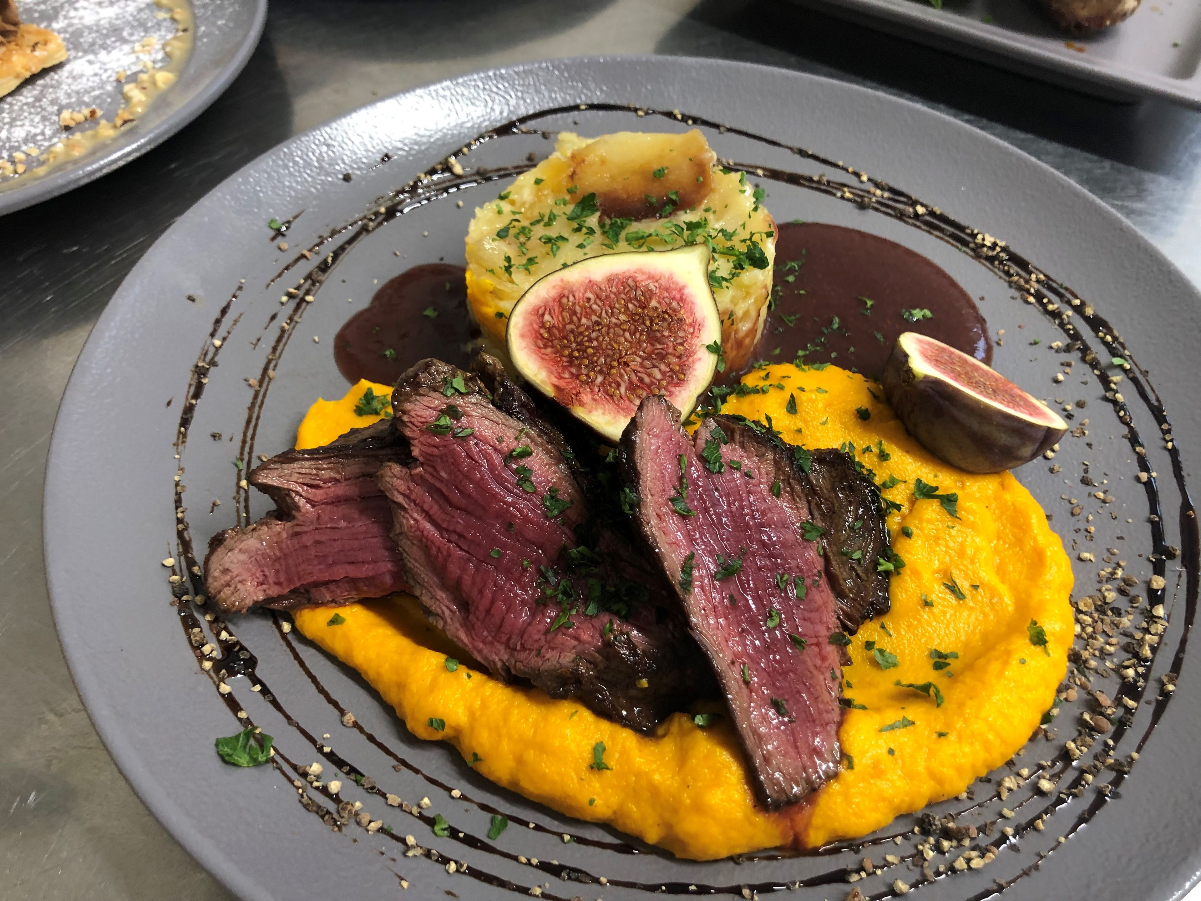 A plate of food with steak, figs, and a yellow puree.