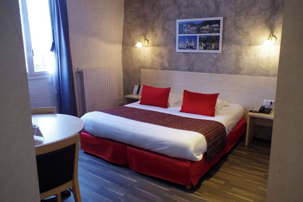 Ett hotellrum med en stor säng, två sängbord, ett litet bord och utsikt över omgivningarna.