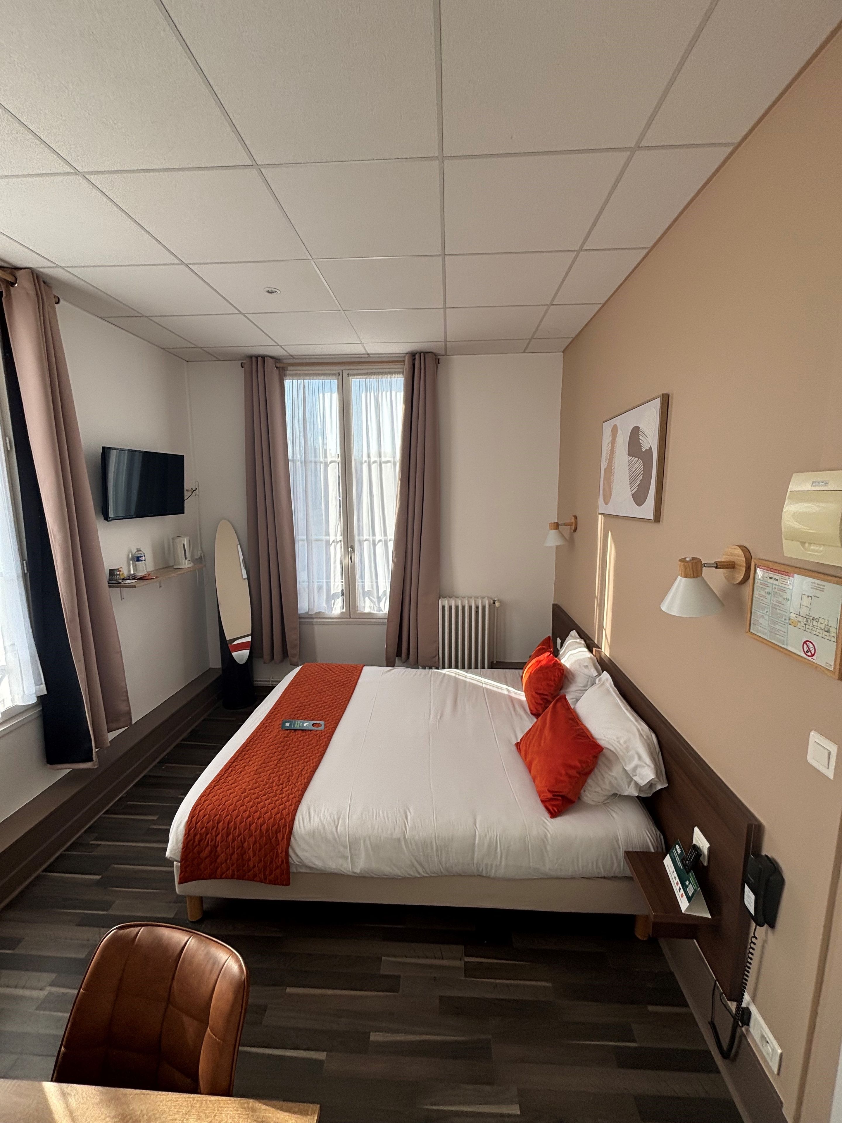A hotel room with a bed, a television, a desk, and a chair.