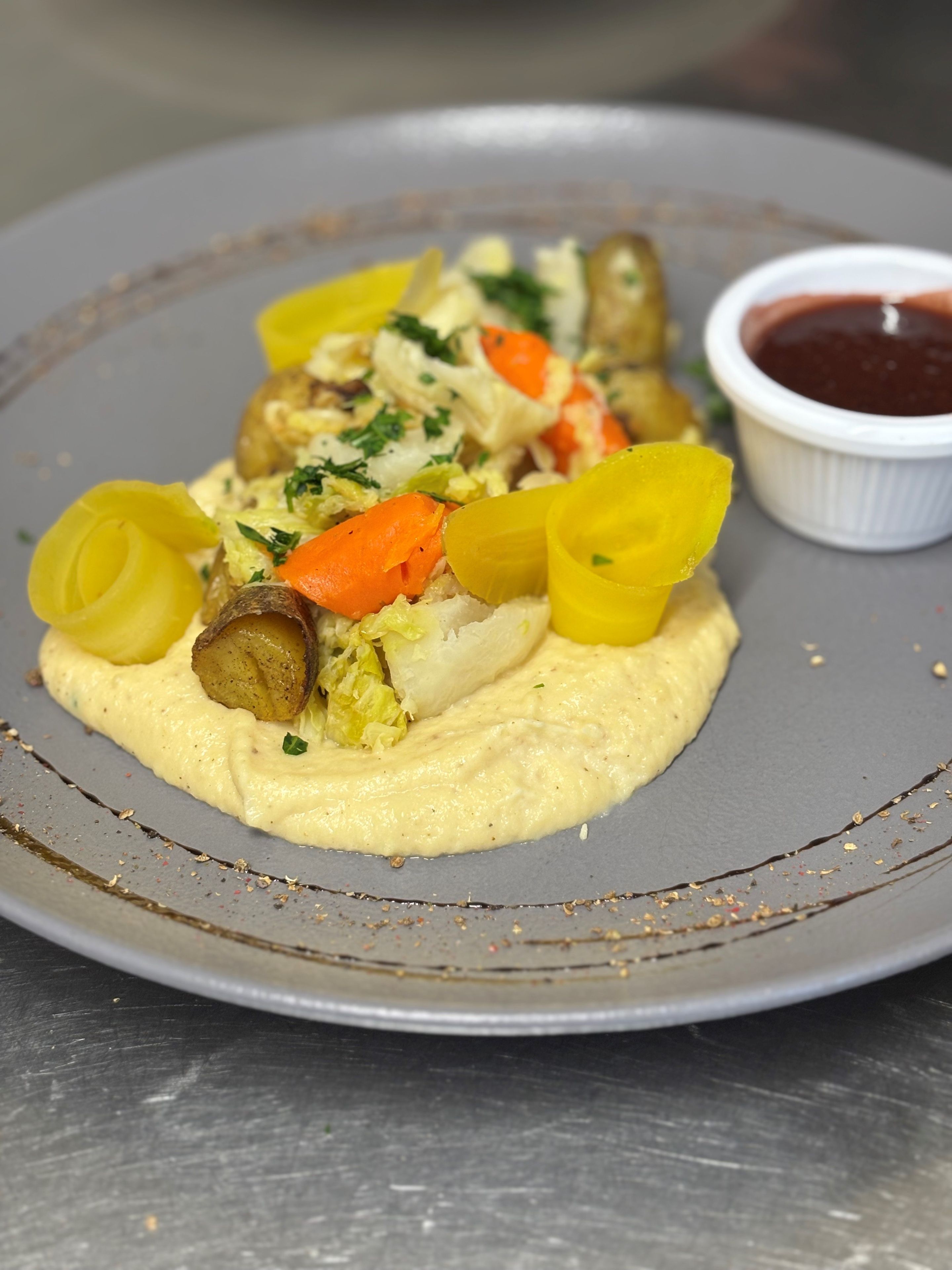 A plate of food with vegetables and a side of sauce.