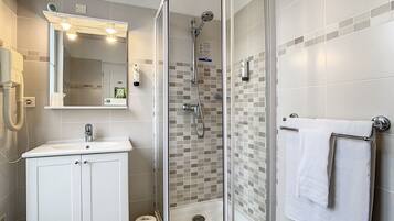A modern bathroom with a glass-enclosed shower, a white sink, and a towel rack.