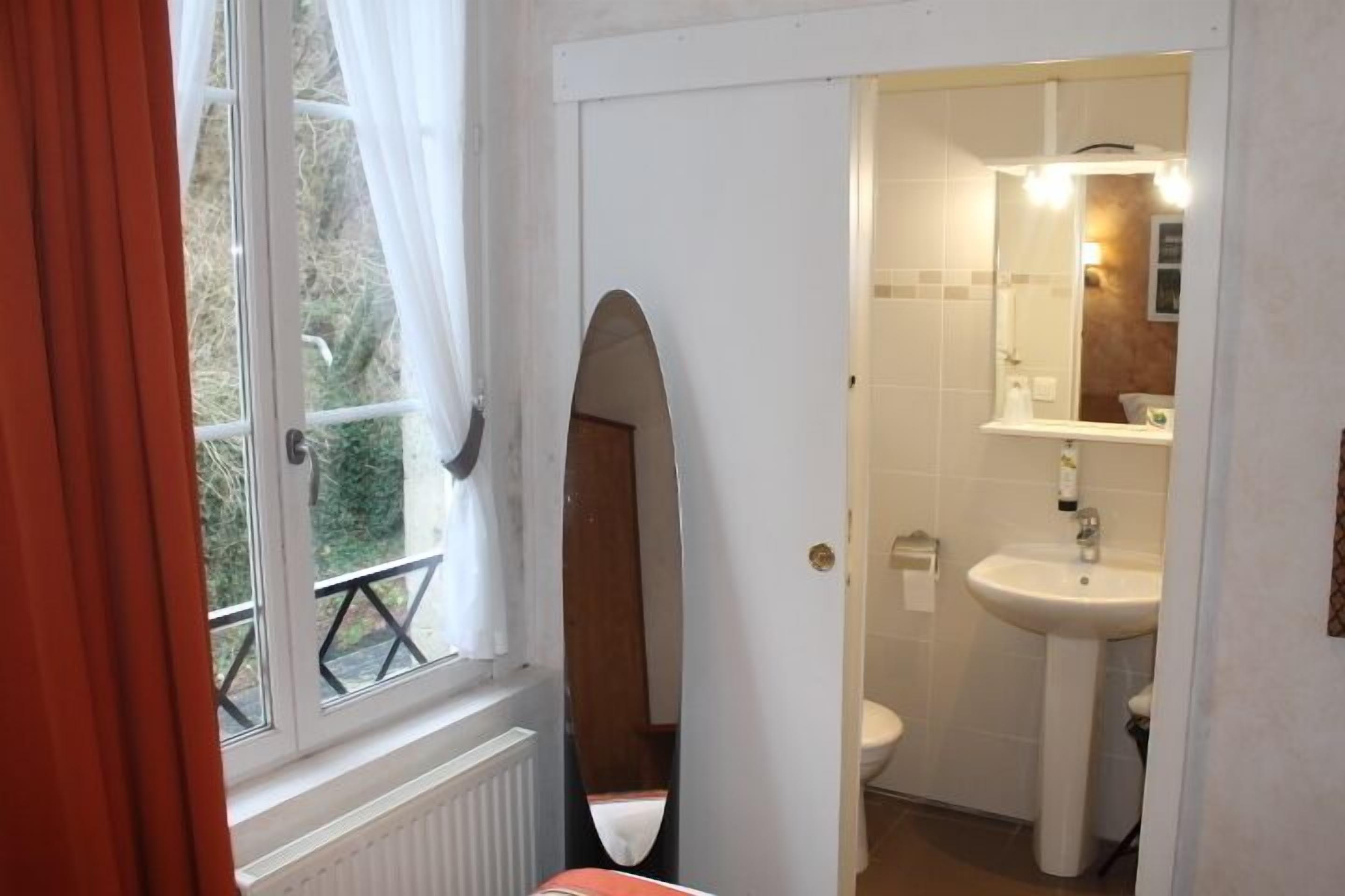 A bathroom with a window, a sink, and a mirror.