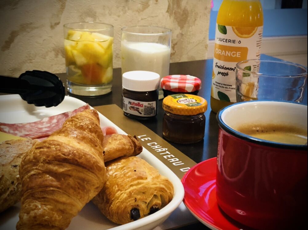 A breakfast setting with croissants, a glass of orange juice, a cup of coffee, and condiments.