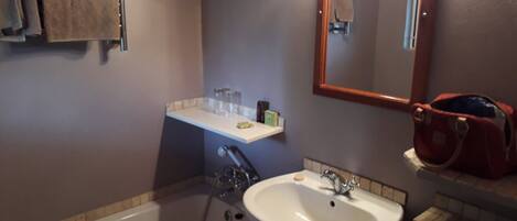 A bathroom with a bathtub, sink, and mirror.