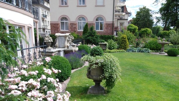 A large, multi-story building with a garden in front.