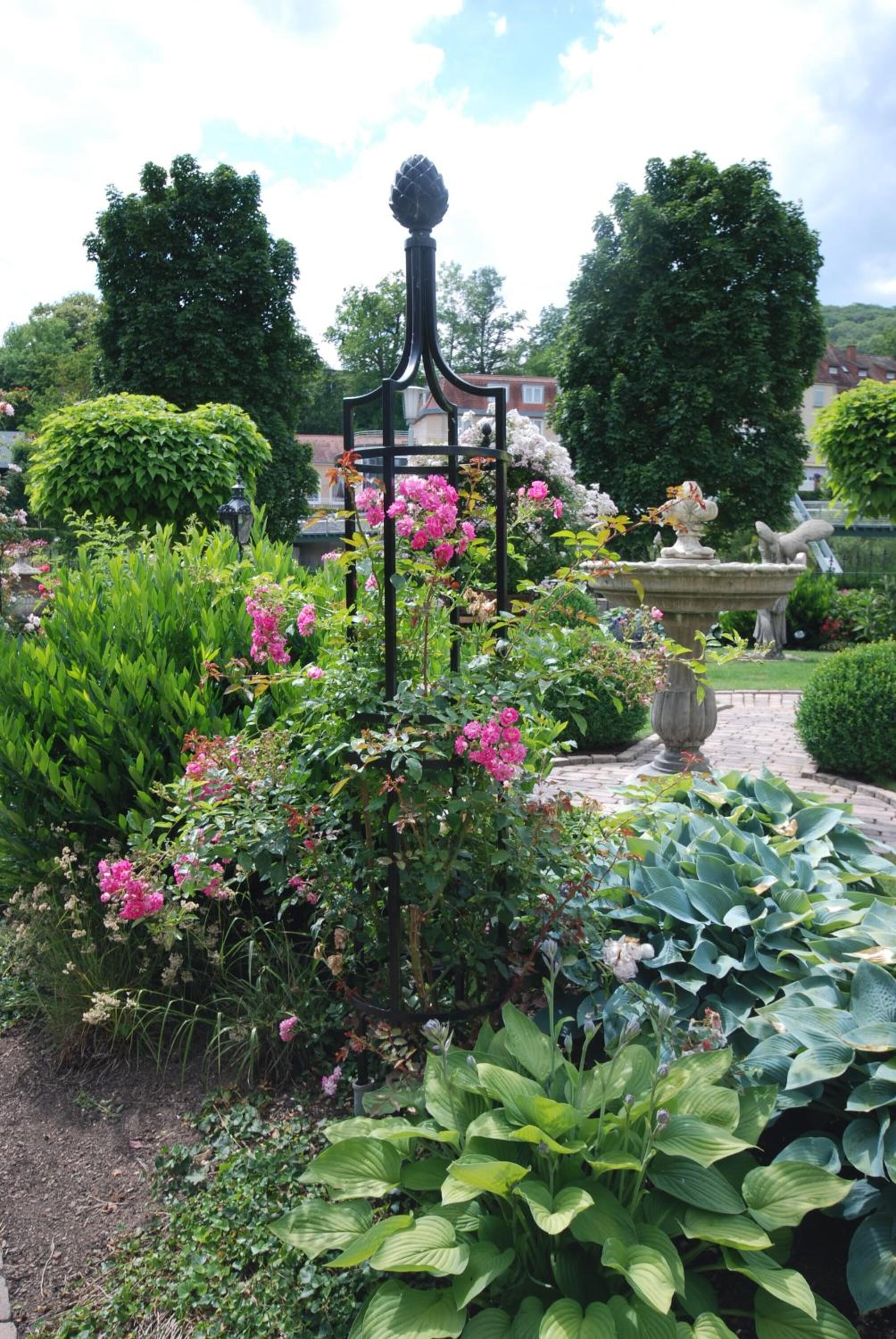 Un jardin agrémenté d’une fontaine, d’une végétation luxuriante et de plantes en fleurs.