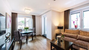 A modern living room with a dining area, large windows, and a sofa.