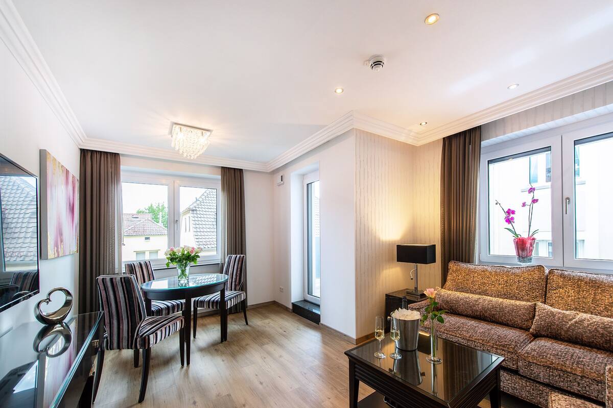 A modern living room with a dining area, large windows, and a sofa.