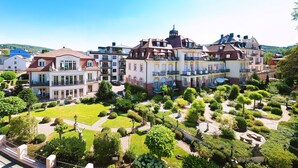 A large, multi-story building with a well-maintained garden and multiple balconies.