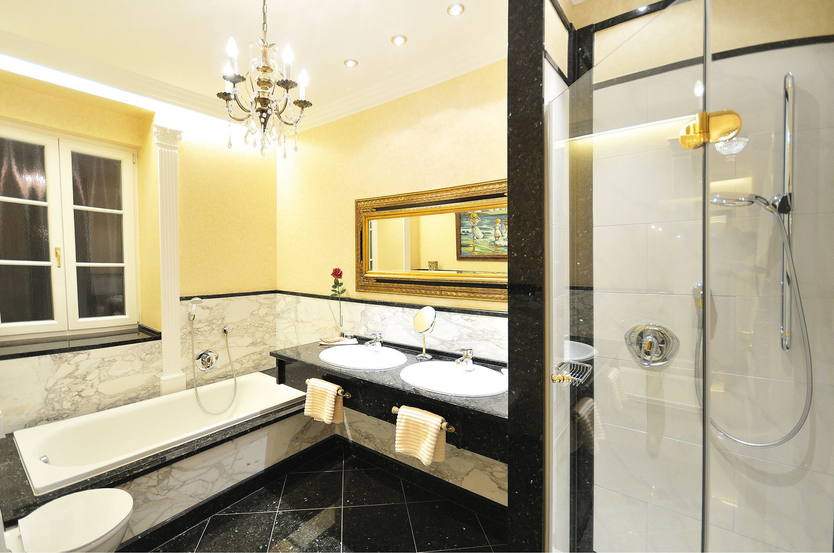 Ein Badezimmer mit Badewanne, zwei Waschbecken, Dusche und einer Chandelier.