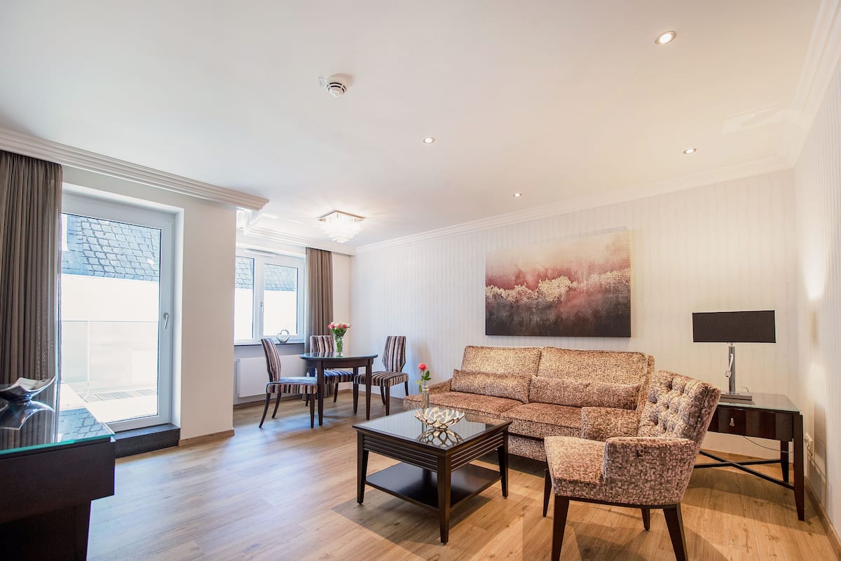 A spacious living room with a sofa, coffee table, and a painting on the wall.