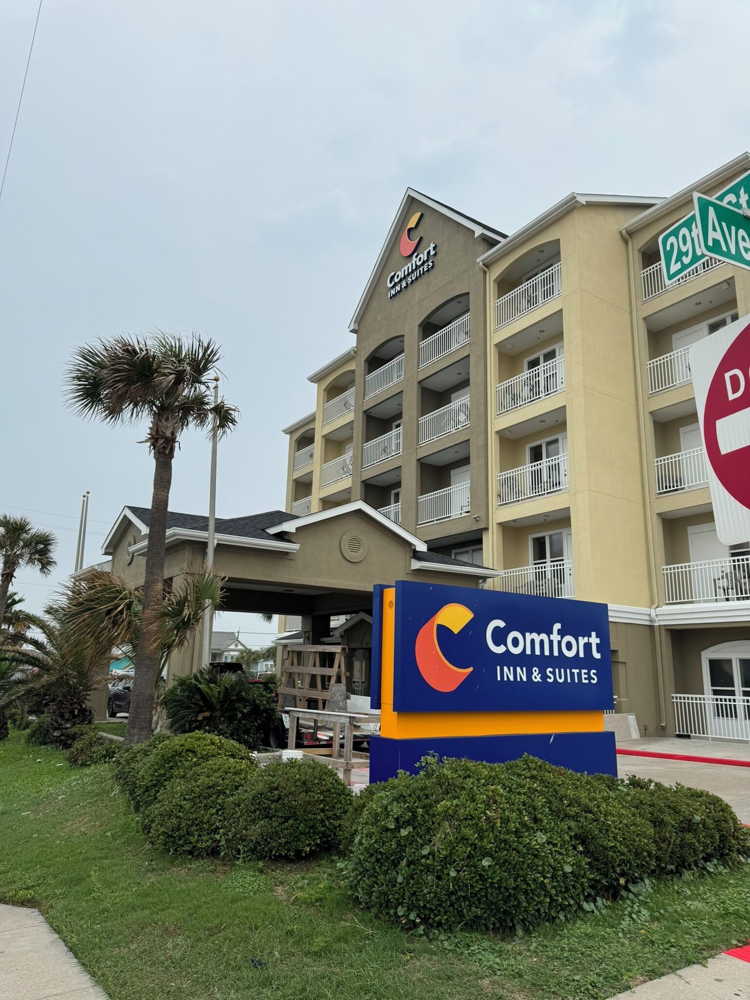 Un hotel Comfort Inn & Suites con un letrero al frente, una señal de calle 29 Avenida y un cartel de no estacionamiento.