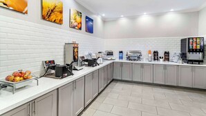 Une cuisine moderne avec des carreaux de métro blancs, un long comptoir doté de divers appareils et un espace dédié au café.