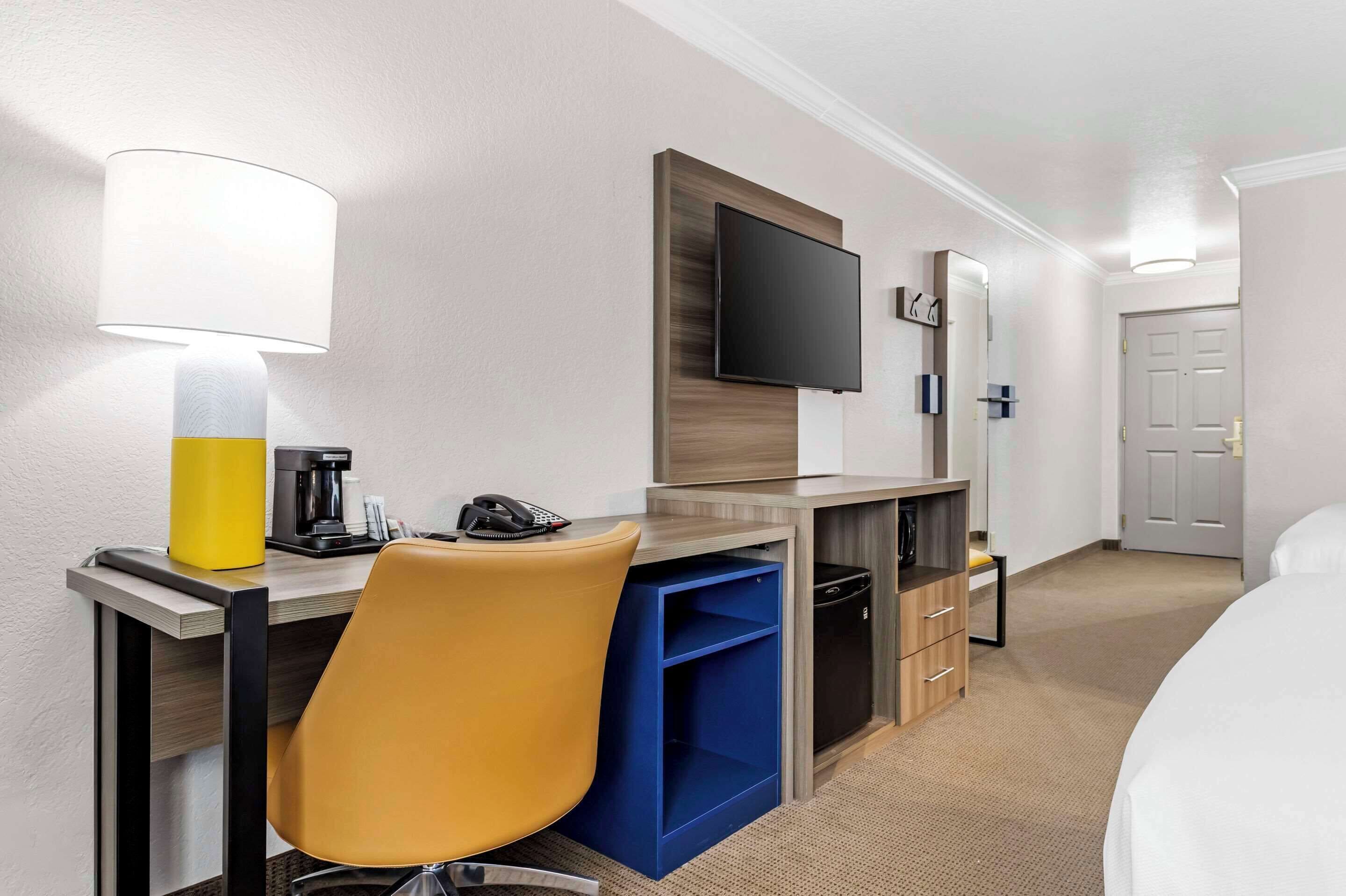 Ein Hotelzimmer mit Schreibtisch, Stuhl, Fernseher und einem Bett.