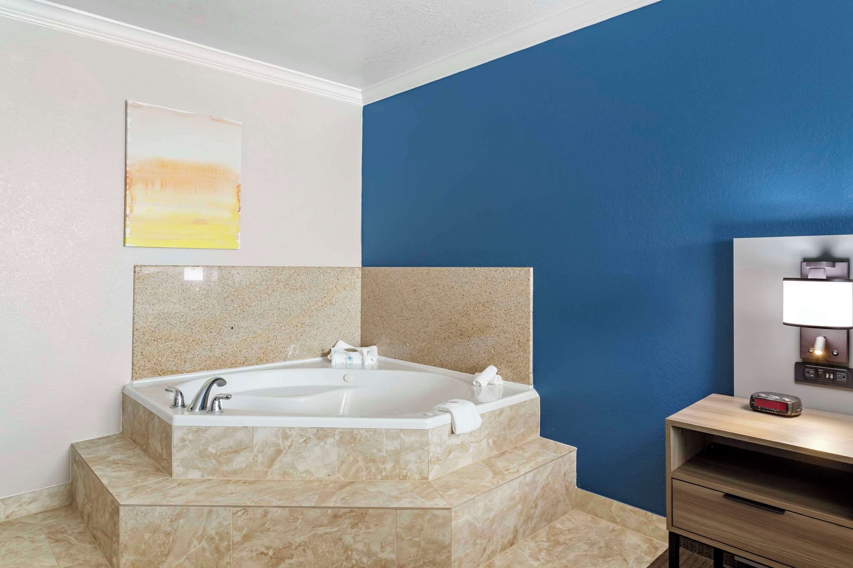 A modern bathroom with a freestanding bathtub, a marble countertop, and a blue accent wall.