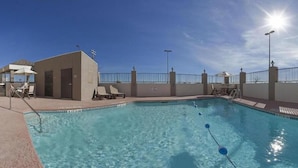 A swimming pool with lounge chairs and umbrellas, a small building, and a clear sky. - Candlewood Suites Ft Stockton by IHG (Fort Stockton)