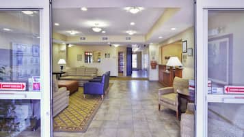 A hotel lobby with seating areas, a reception desk, and an automatic sliding door.