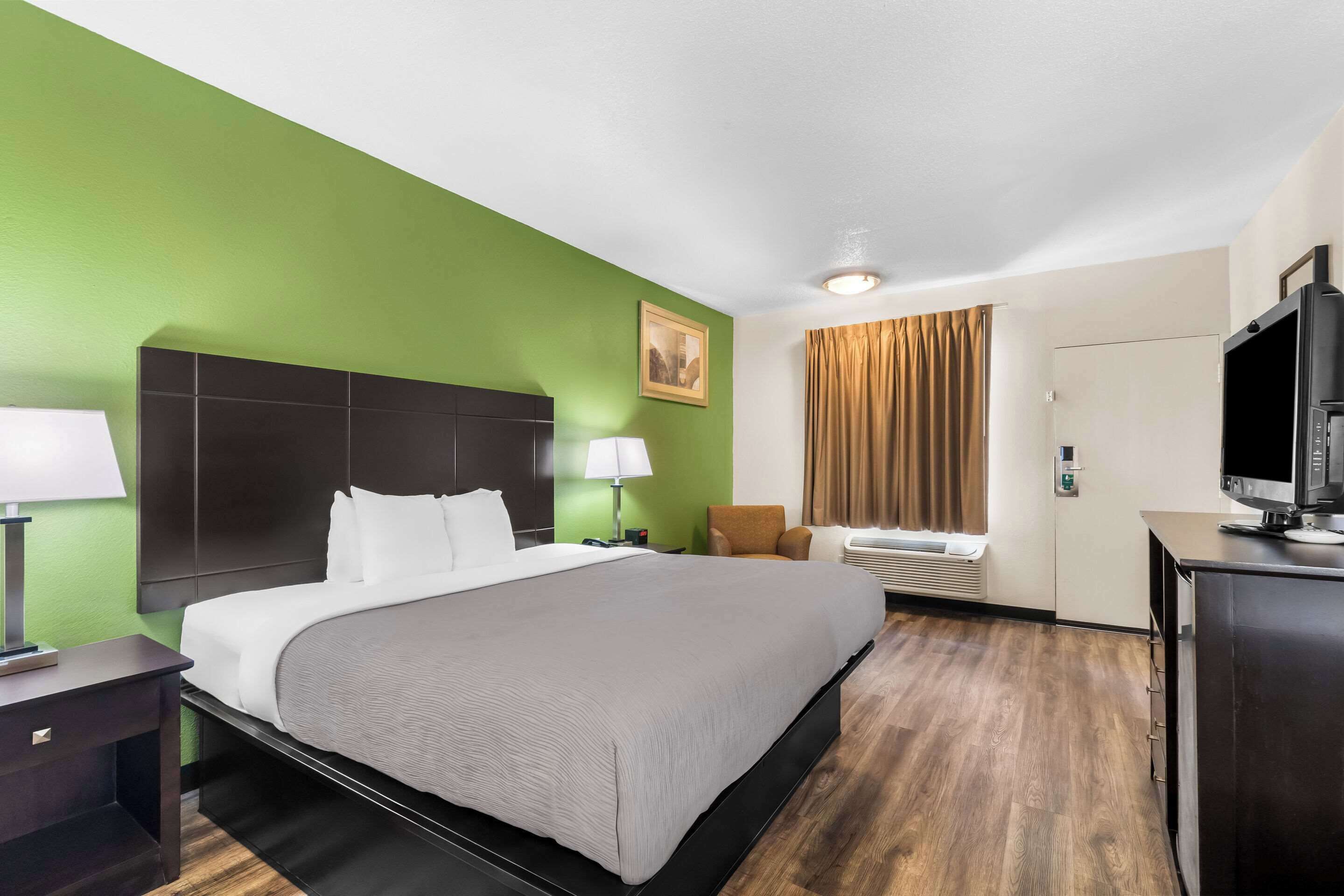 A hotel room with a large bed, a flat-screen TV, a desk, and a chair.