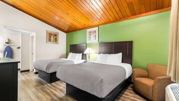 Habitación de hotel con dos camas, un escritorio, una silla y un techo con vigas de madera.